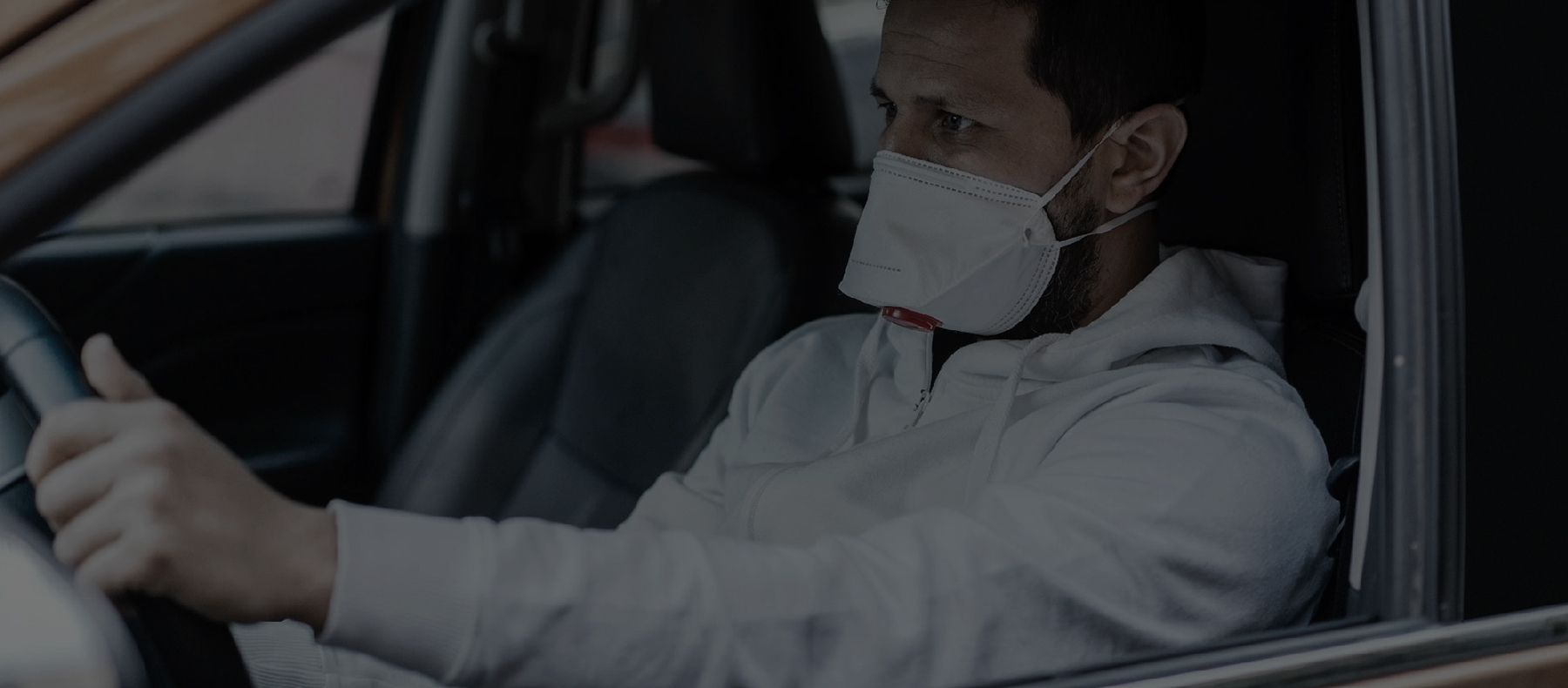 Man wearing a mask while driving alone in his car