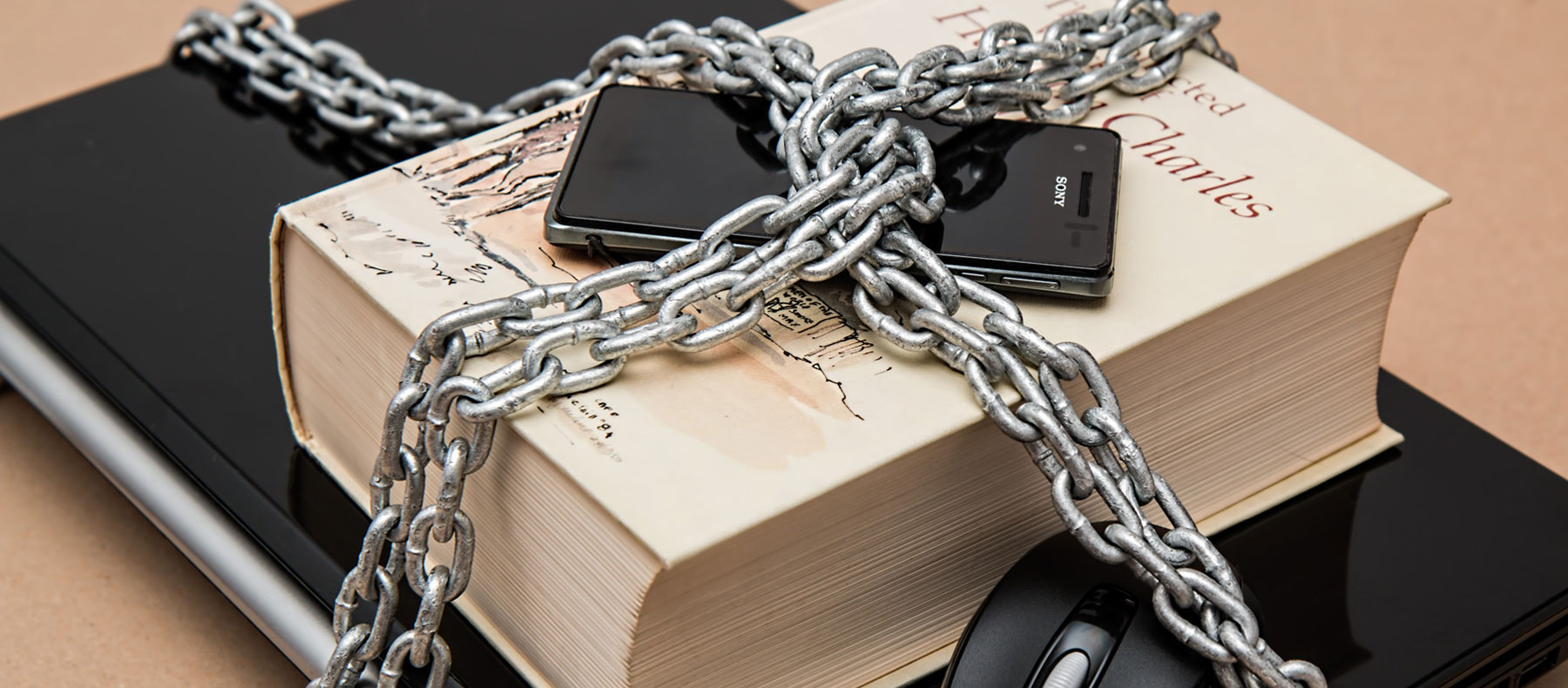 Chain ,inked around large book with cellphone on top