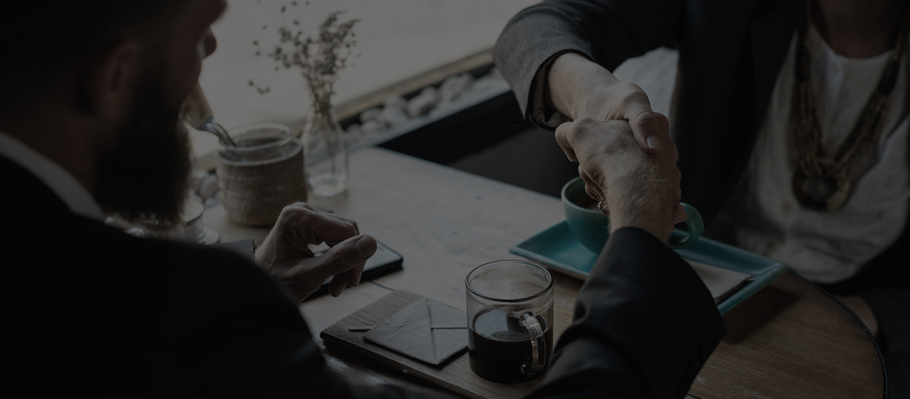 Men shaking hands at wooden table